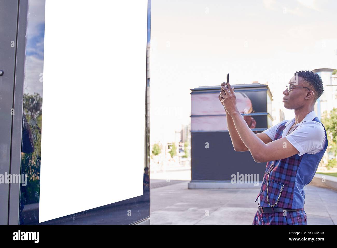 Young african american man taking photo with the smart phone to customizable advertising poster. Stock Photo