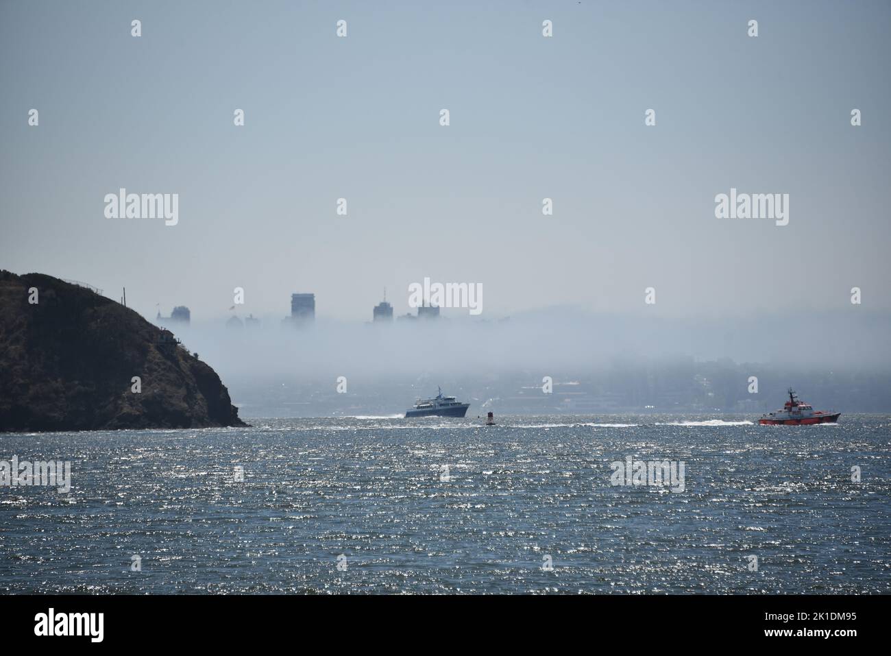 A wonderful large format panoramic view of San Francisco in dense fog from across the sparkling bay, with cruising boats in the foreground. Stock Photo