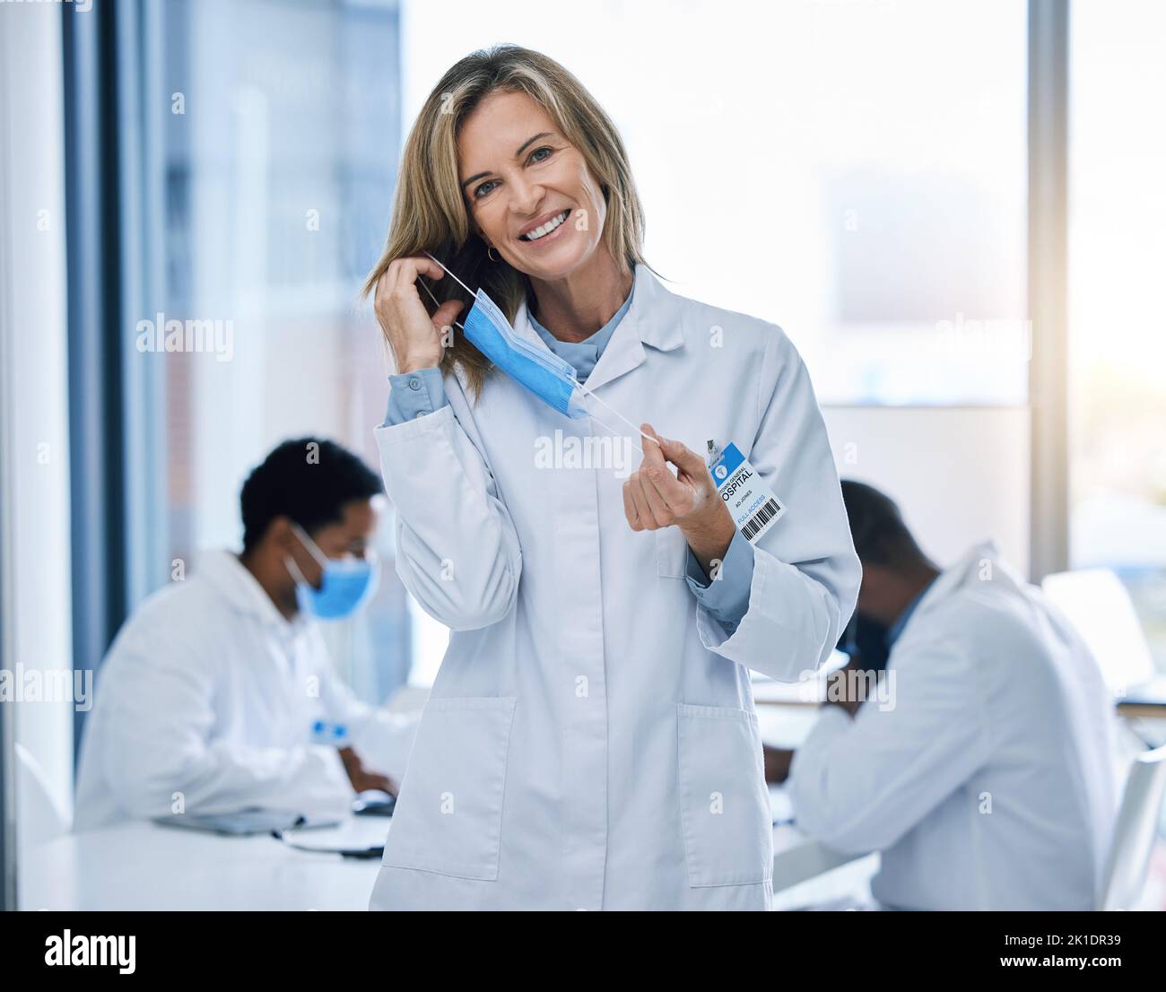 Doctor removing covid face mask after end of pandemic, happy after surgery success and freedom from virus. Face portrait of healthcare person and Stock Photo