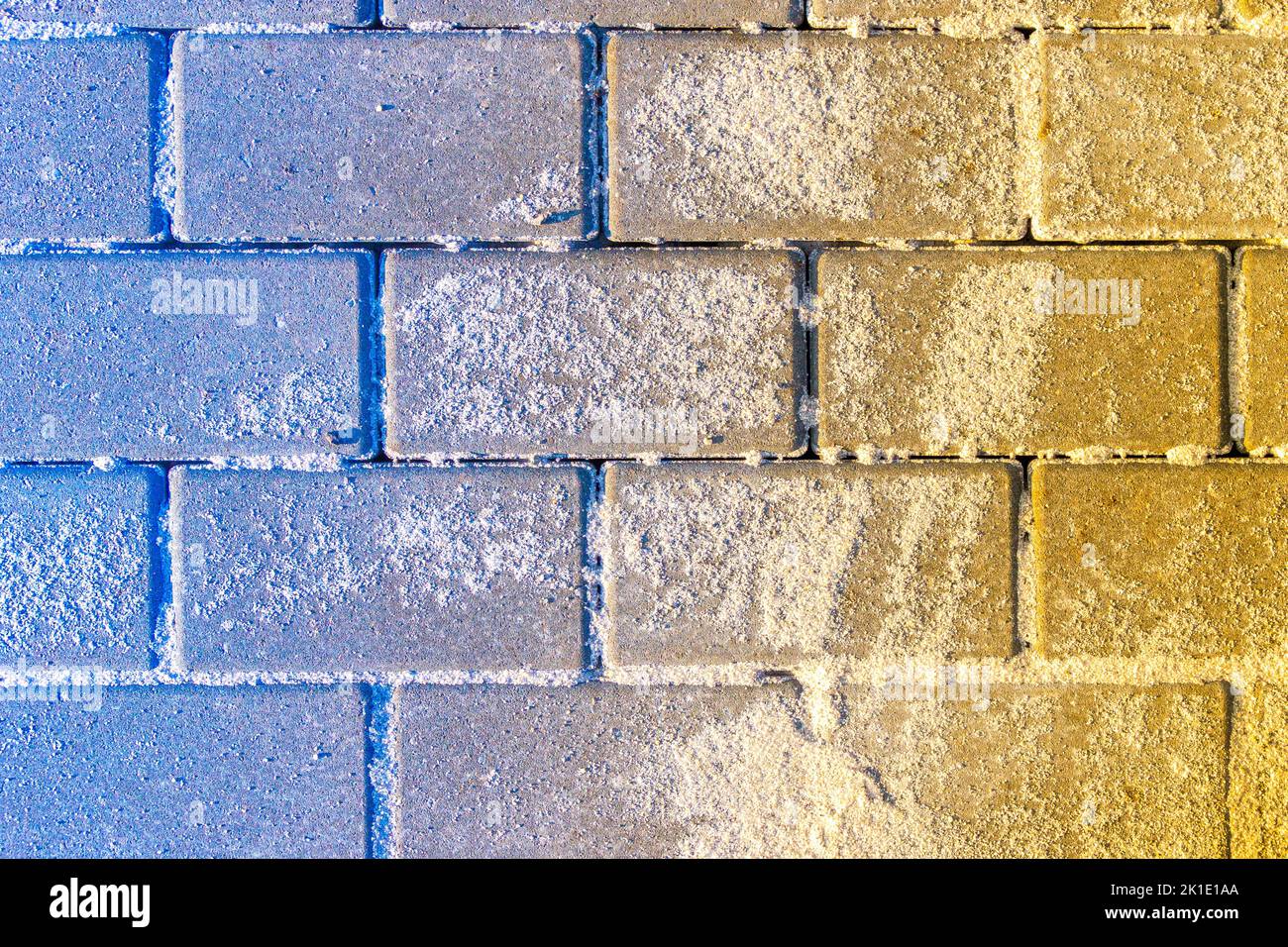 blue-yellow hailstone superimposed on stacked paving slabs sprinkled with sand, selective focus Stock Photo