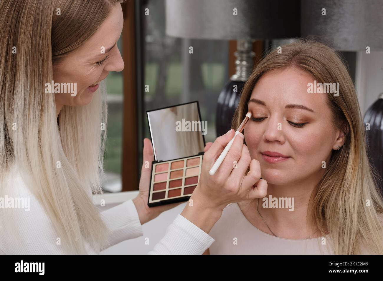 Artist with palette doing nude eye make-up in beauty salon. Woman applying eyeshadow powder. Processional look natural female Stock Photo