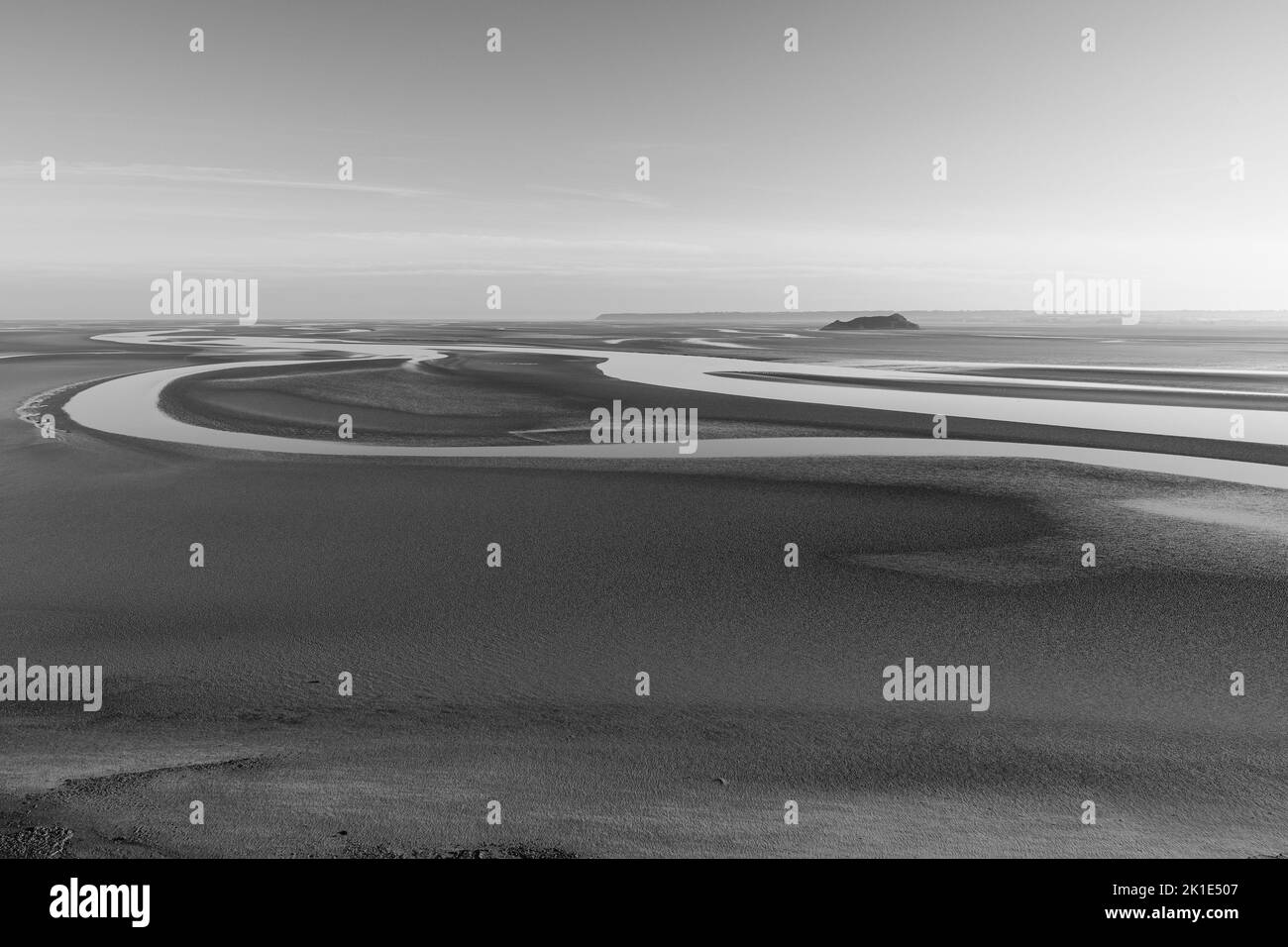 A beautiful sunset over the beach during low tide, grayscale shot Stock
