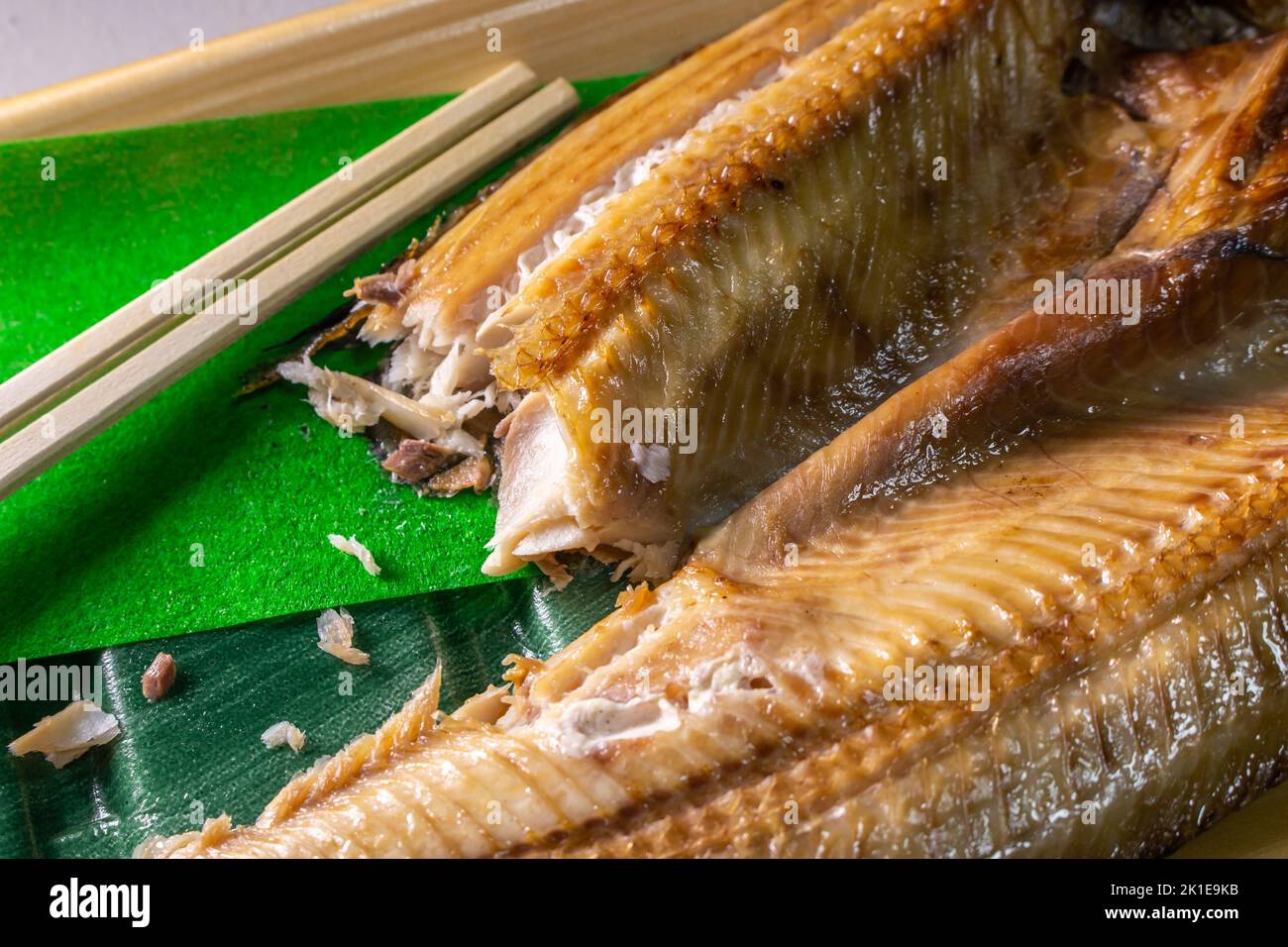 Closeup Japanese Aji no Hiraki (dried and salted horse mackerel) in a food container with Waribashi (Hashi). Stock Photo
