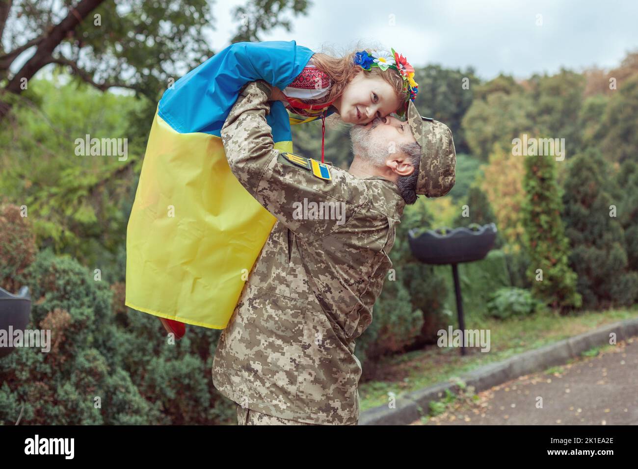 The Ukrainian military is holding his daughter in her arms, she is wrapped in the flag of Ukraine. Stock Photo