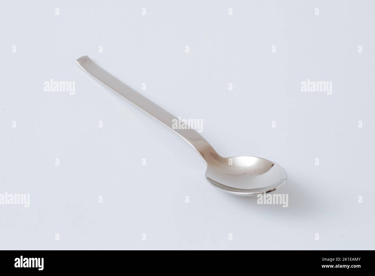 Stainless steel teaspoon on white background, kitchenware, copy space, close-up. Stock Photo