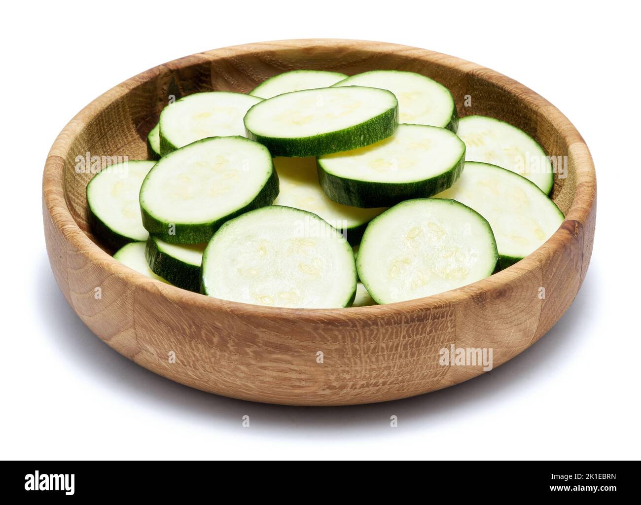 Sliced zucchini circles in wooden bowl isolated on white background Stock Photo