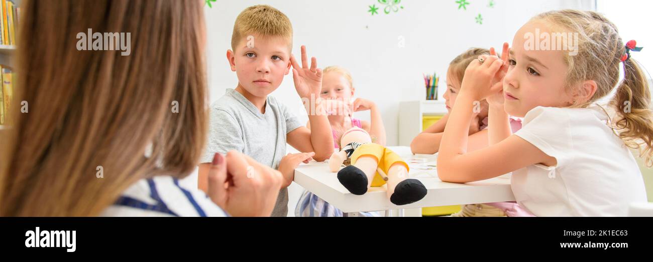Child occupational therapy session. Group of children doing playful exercises with their therapist. Stock Photo