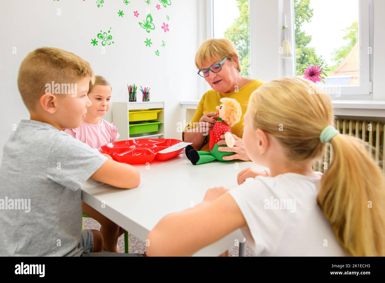 Children speech therapy concept. Children practicing correct pronunciation with a female speech therapist. Group therapy. Stock Photo