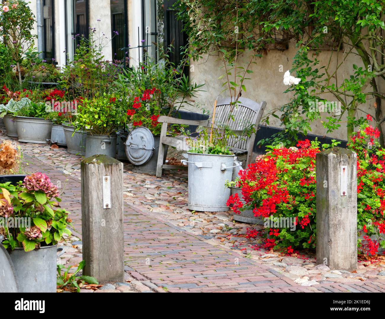 Small street near to the fortified wall with flowers in pots and buckets in the center of Elburg in the Netherlands. Stock Photo