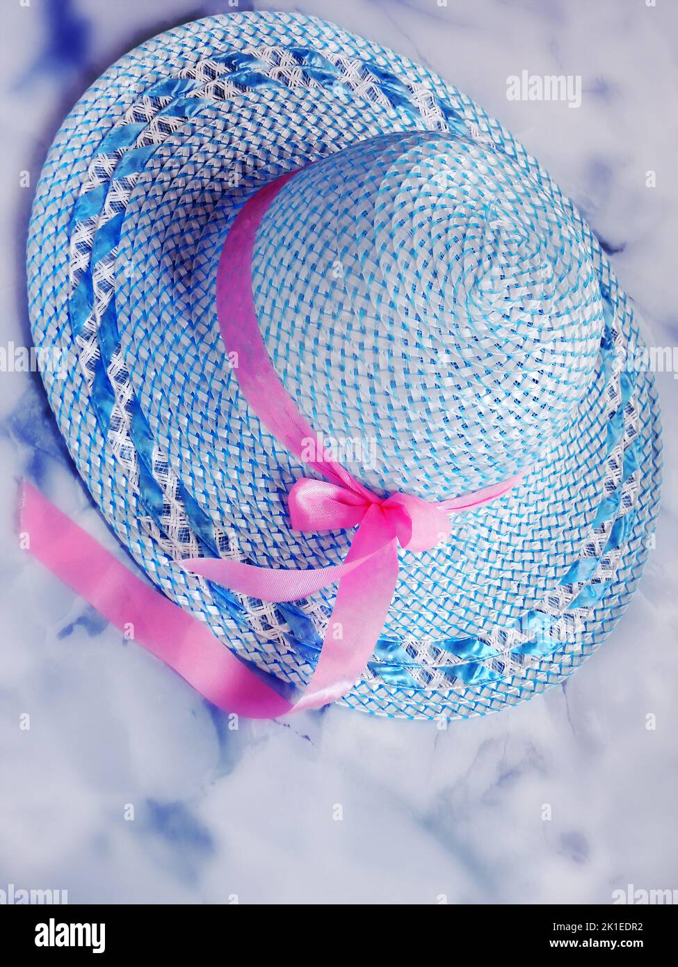 light blue romantic summer  straw-hat with pink ribbon lying on a marble background, Stock Photo