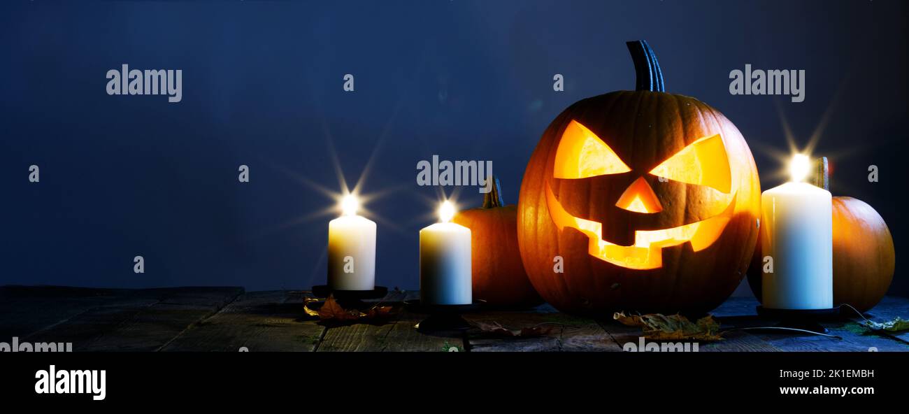 Halloween night glowing pumpkins and candles on blue background Stock Photo
