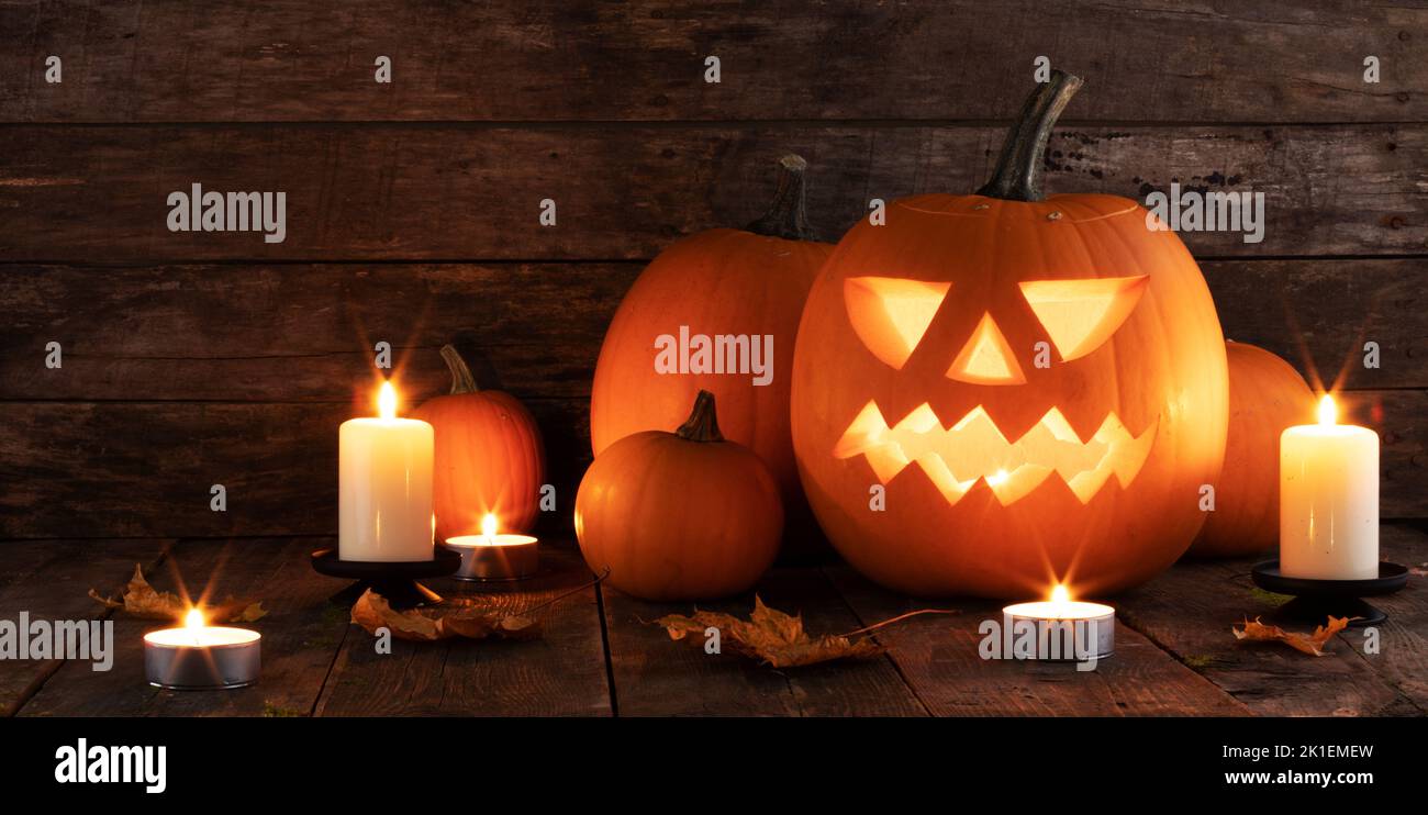 Halloween pumpkins candles and dry maple leaves on wooden background Stock Photo