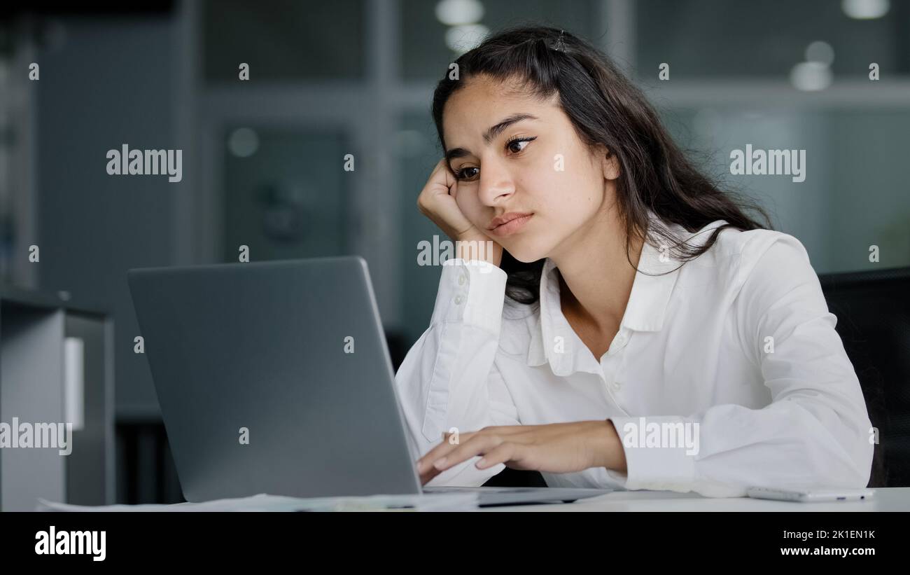 Bored sad lazy young indian woman manager sitting in office unmotivated uninterested in boring laptop work overworked tired sleepy businesswoman Stock Photo