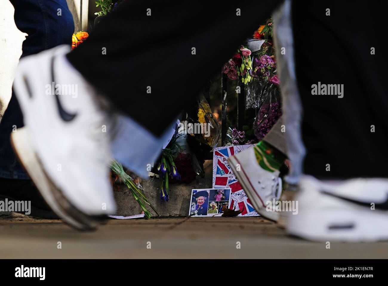 Members of the public walk past pictures of Queen Elizabeth II near Buckingham Palace in London, following the death of Queen Elizabeth II. Picture date: Sunday September 18, 2022. Stock Photo