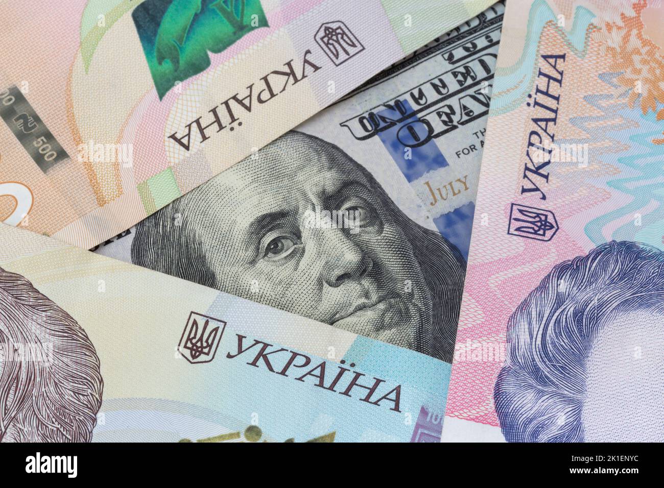 close up of one hundred US dollars banknote surrounded by Ukrainian hrivnya banknotes Stock Photo