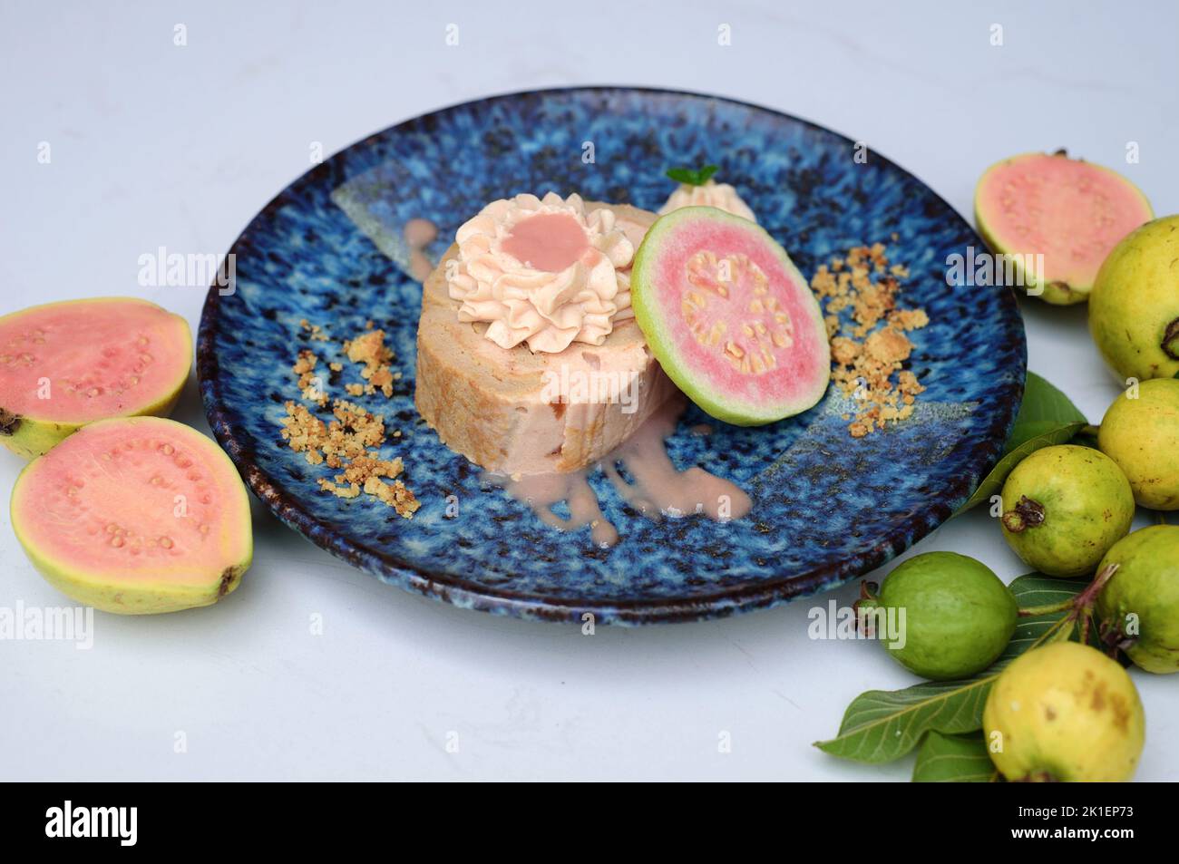 Guava Roll Cake on blue plate on light background with ripe guava fruit Stock Photo