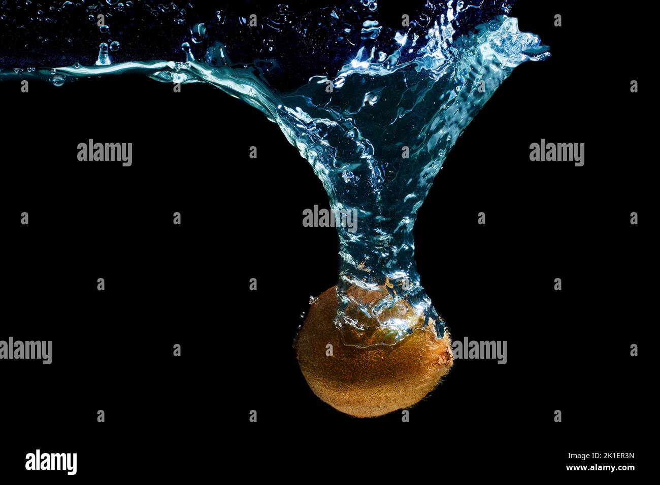 Whole kiwi dropped in water with a whirlpool isolated on black background Stock Photo