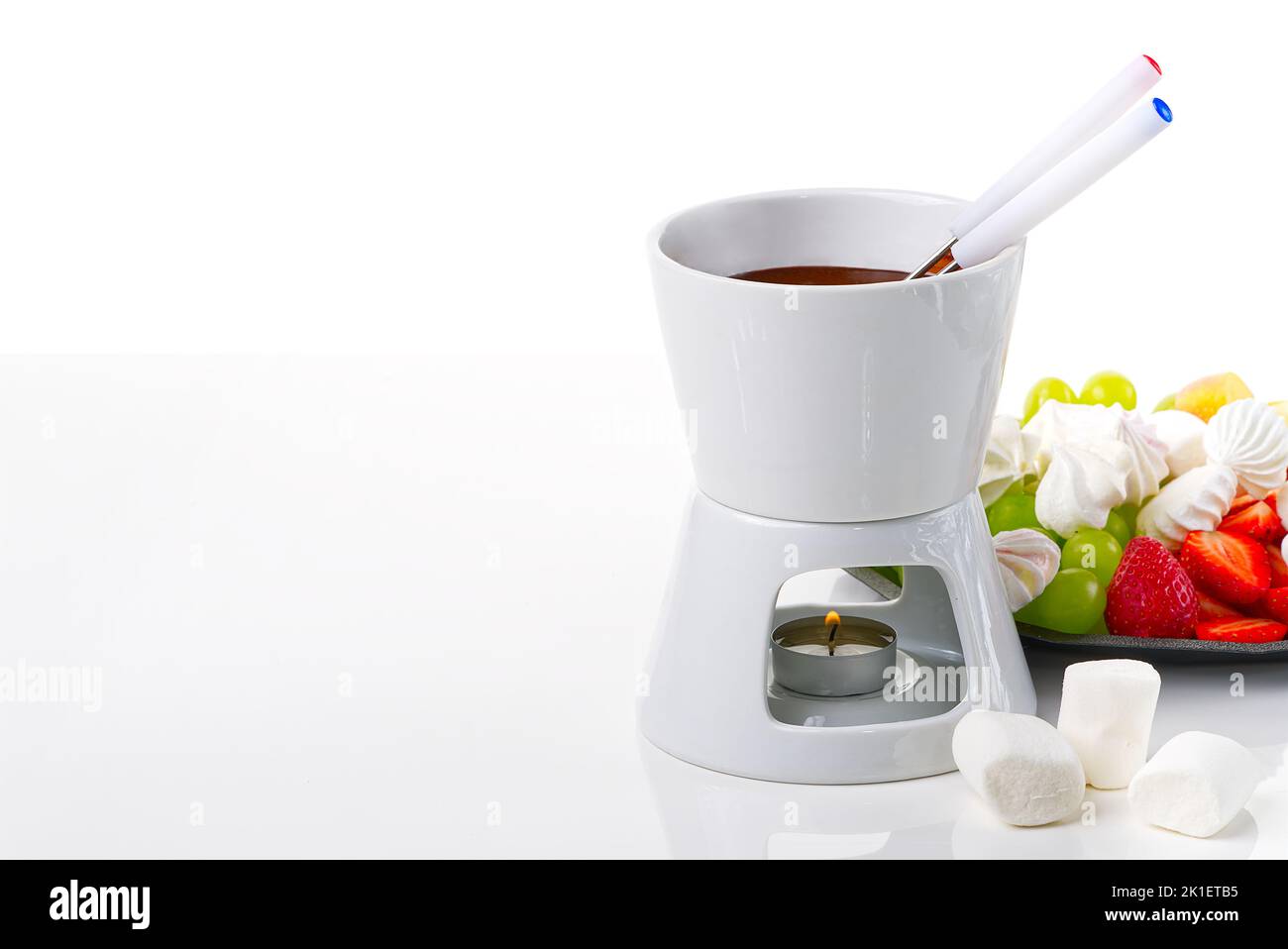 Chocolate fondue. fruits dipping into bowl with chocolate on white