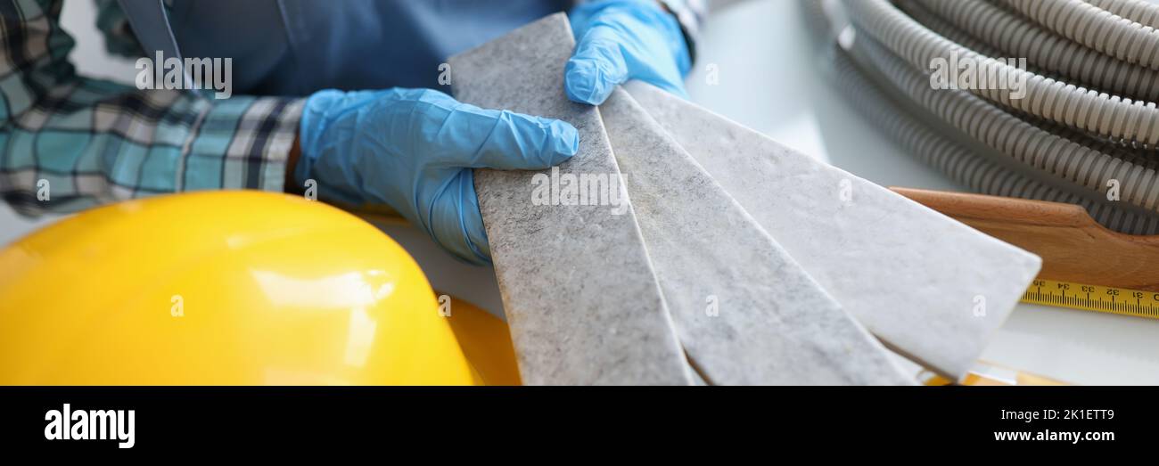 Builder holding gray tiles for bathroom in workshop closeup Stock Photo