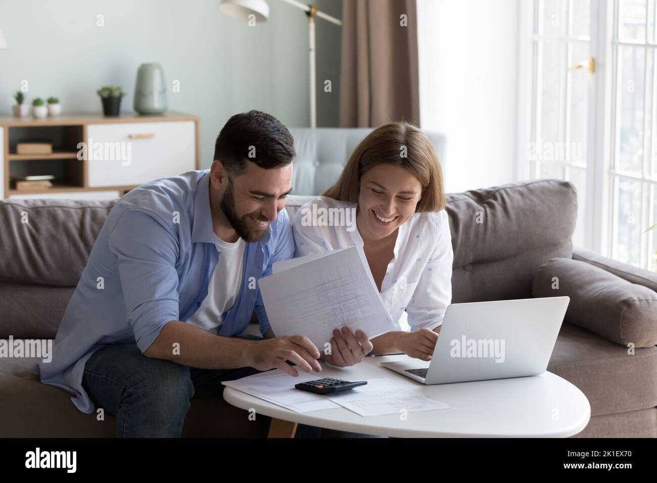 Cheerful young millennial husband and wife doing domestic paperwork Stock Photo