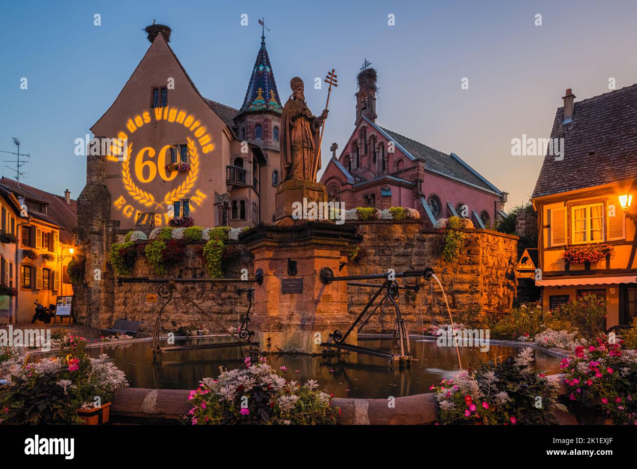 A summer evening on the main square (with the fountain of Saint-Léon) in the village of Eguisheim in French Alsace. The 60th edition of the Winegrower Stock Photo