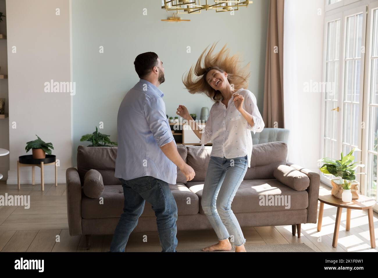Happy beautiful girlfriend teaching man to dance at home Stock Photo
