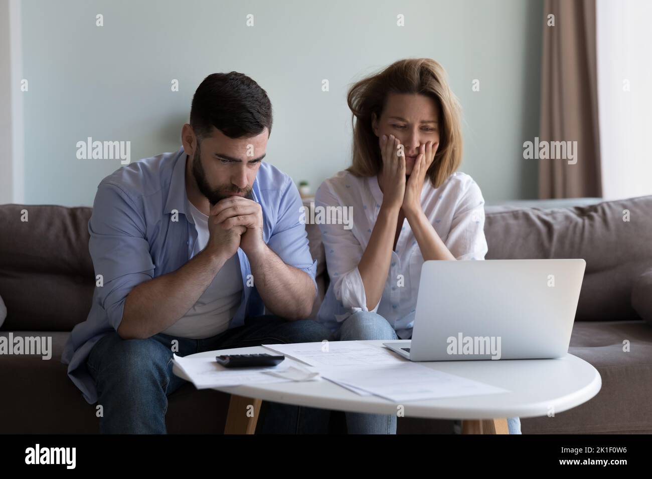 Frustrated worried millennial husband and wife reading bankrupt message Stock Photo