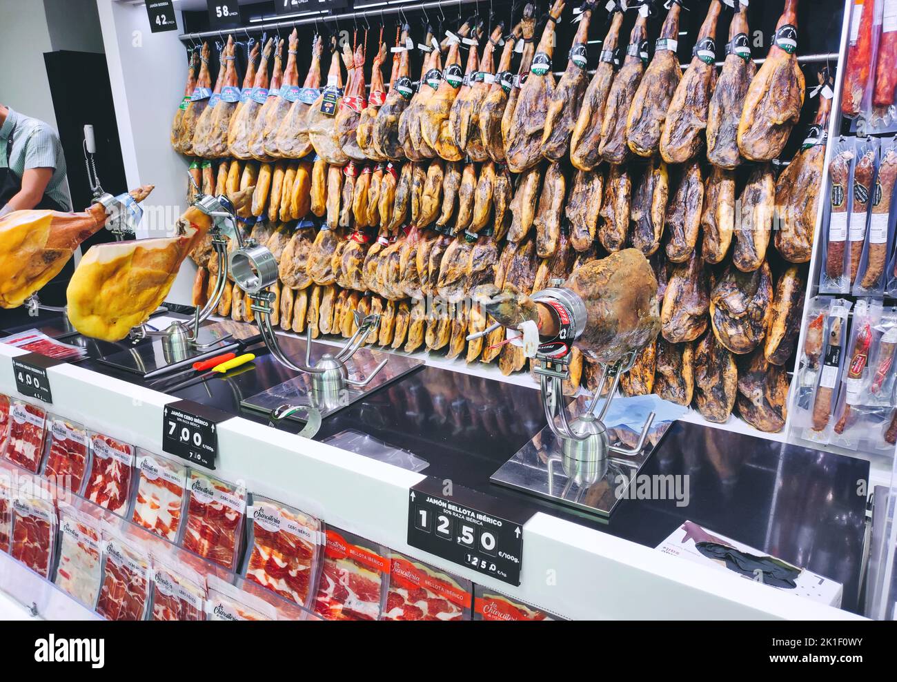 June 08 2022 - Seville, Spain: Hanging cured hams on the wall in a Spanish supermarket Stock Photo
