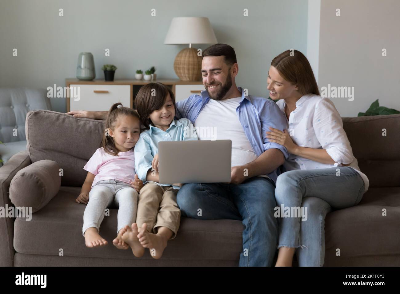 Happy family couple and cute cheerful kids using laptop Stock Photo