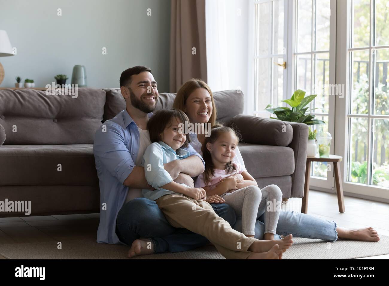 Cheerful Caucasian parents and boy and girl resting on floor Stock Photo