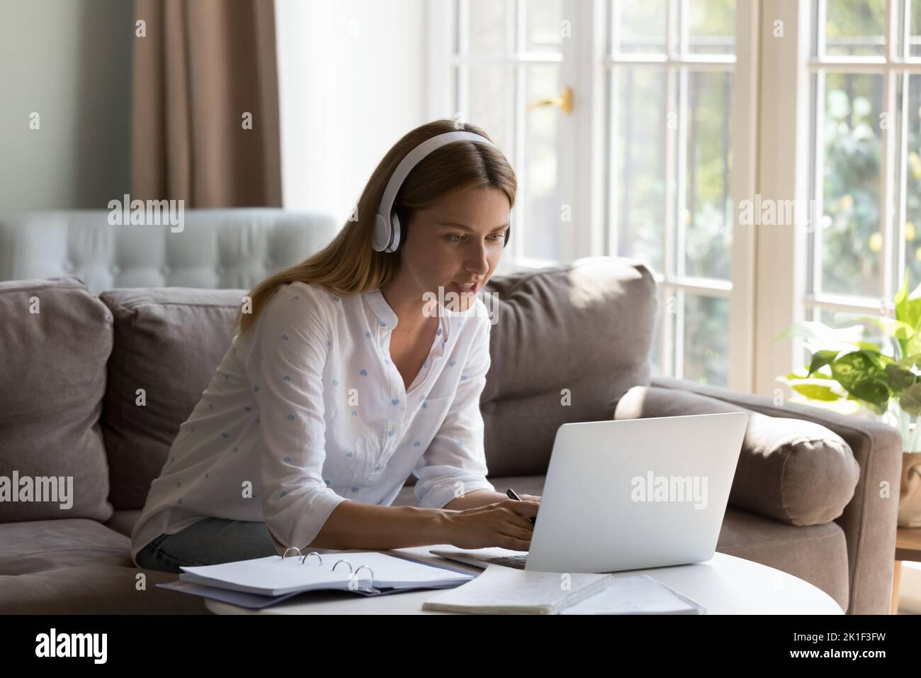 Happy engaged student woman in wireless headset studying from home Stock Photo