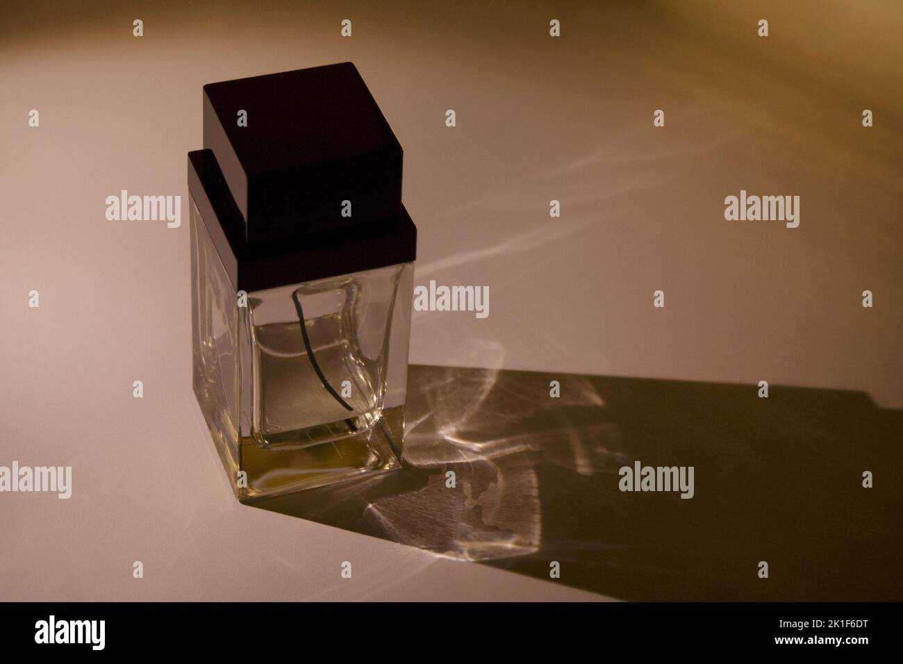 Glass perfume bottle container with a long shadow on dark background Stock Photo