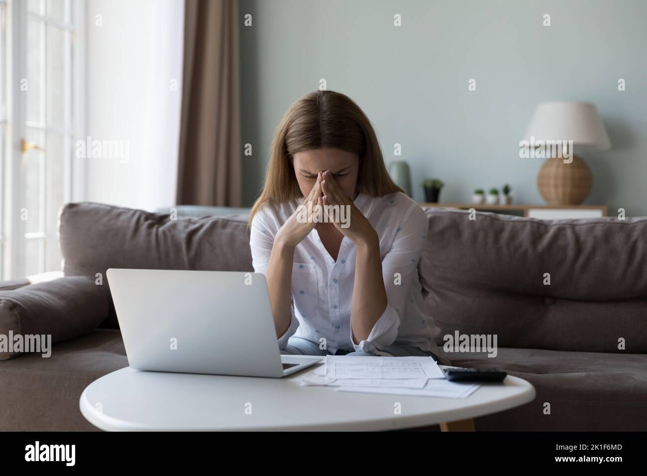 Desperate depressed millennial woman sitting at paper document Stock Photo