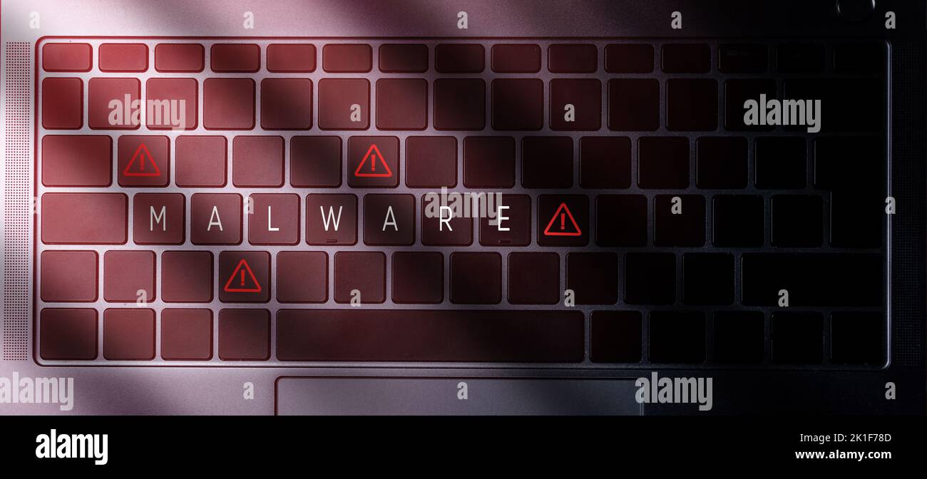Banner top view of laptop keyboard with 'malware' message on buttons and red light. Security alert data protection business technology. Stock Photo