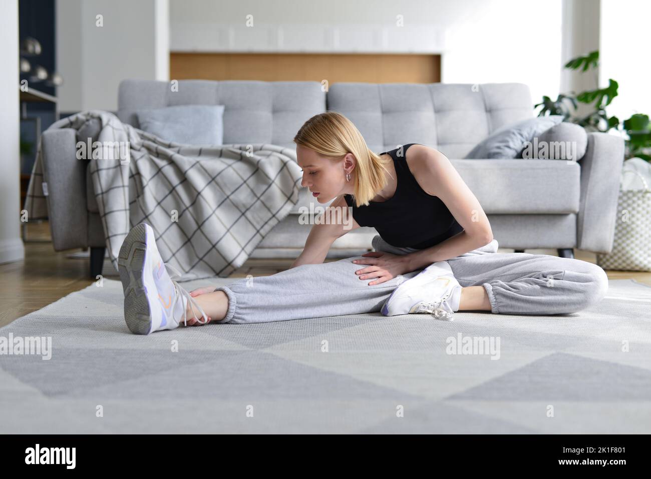 Woman doing stretching exercise at home. Stock Photo