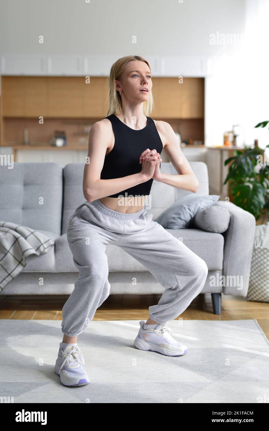 Woman performs squatting exercises at home. Stock Photo