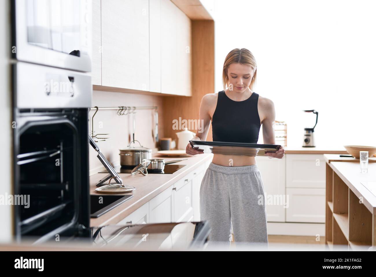 Woman carries tray to put in oven for baking. Stock Photo