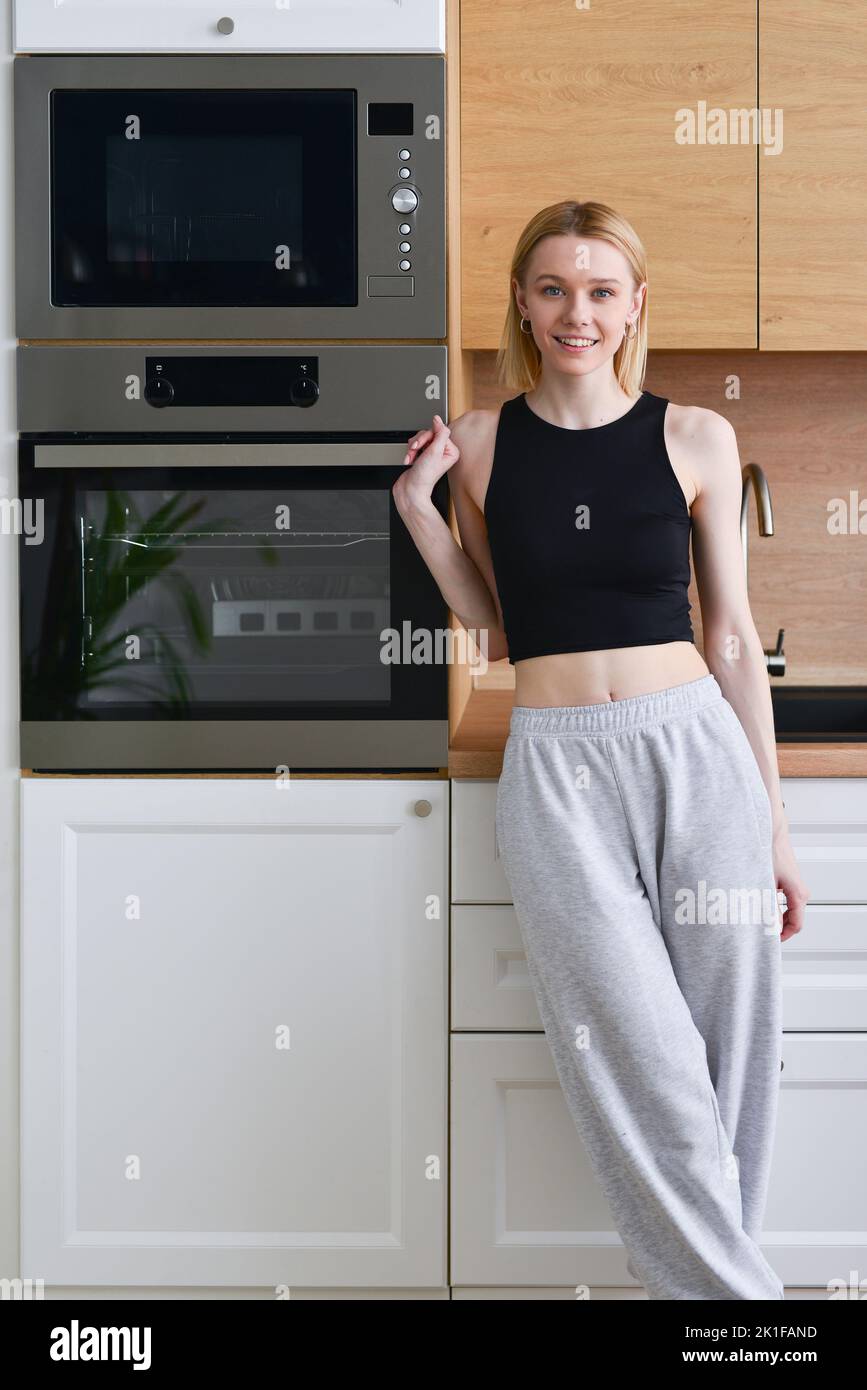 Sporty-looking woman standing at home in kitchen. Stock Photo