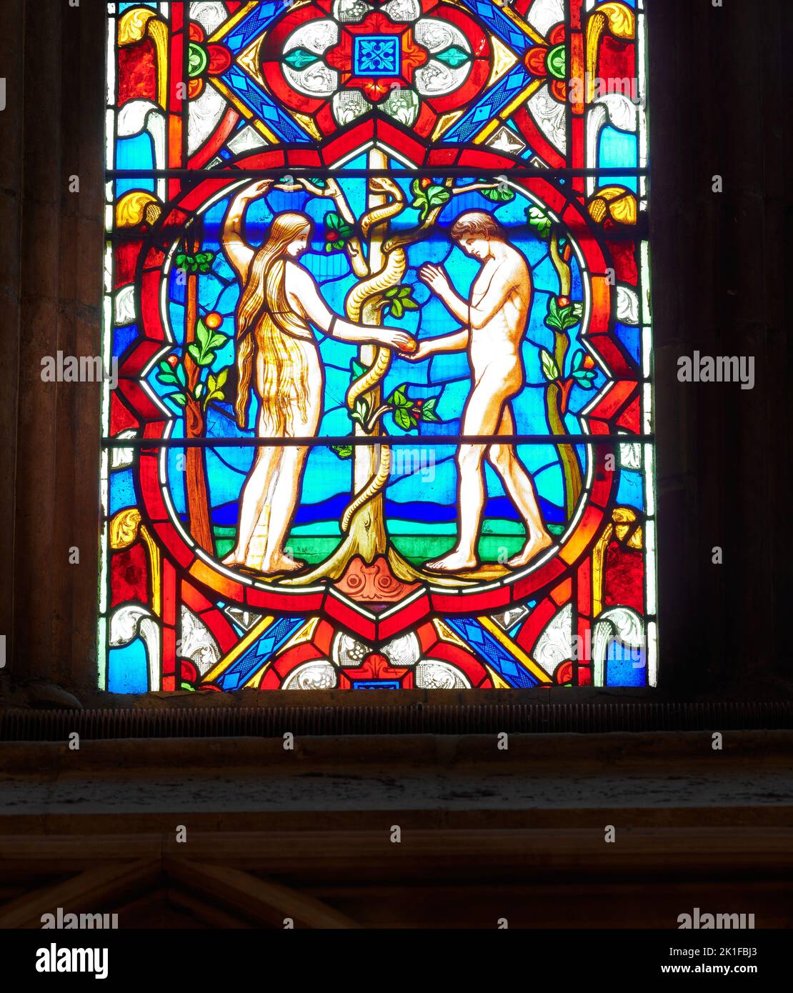 Eve and Adam and the serpent, with an apple in the garden of Eden; a stained glass window at Lincoln cathedral, England. Stock Photo