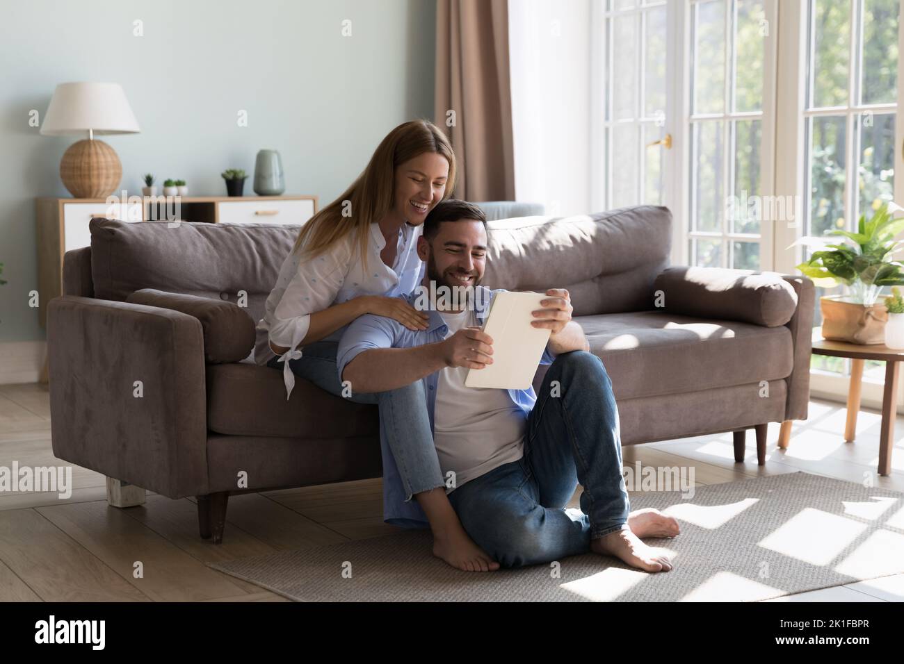 Happy millennial attractive couple of homeowners using tablet Stock Photo