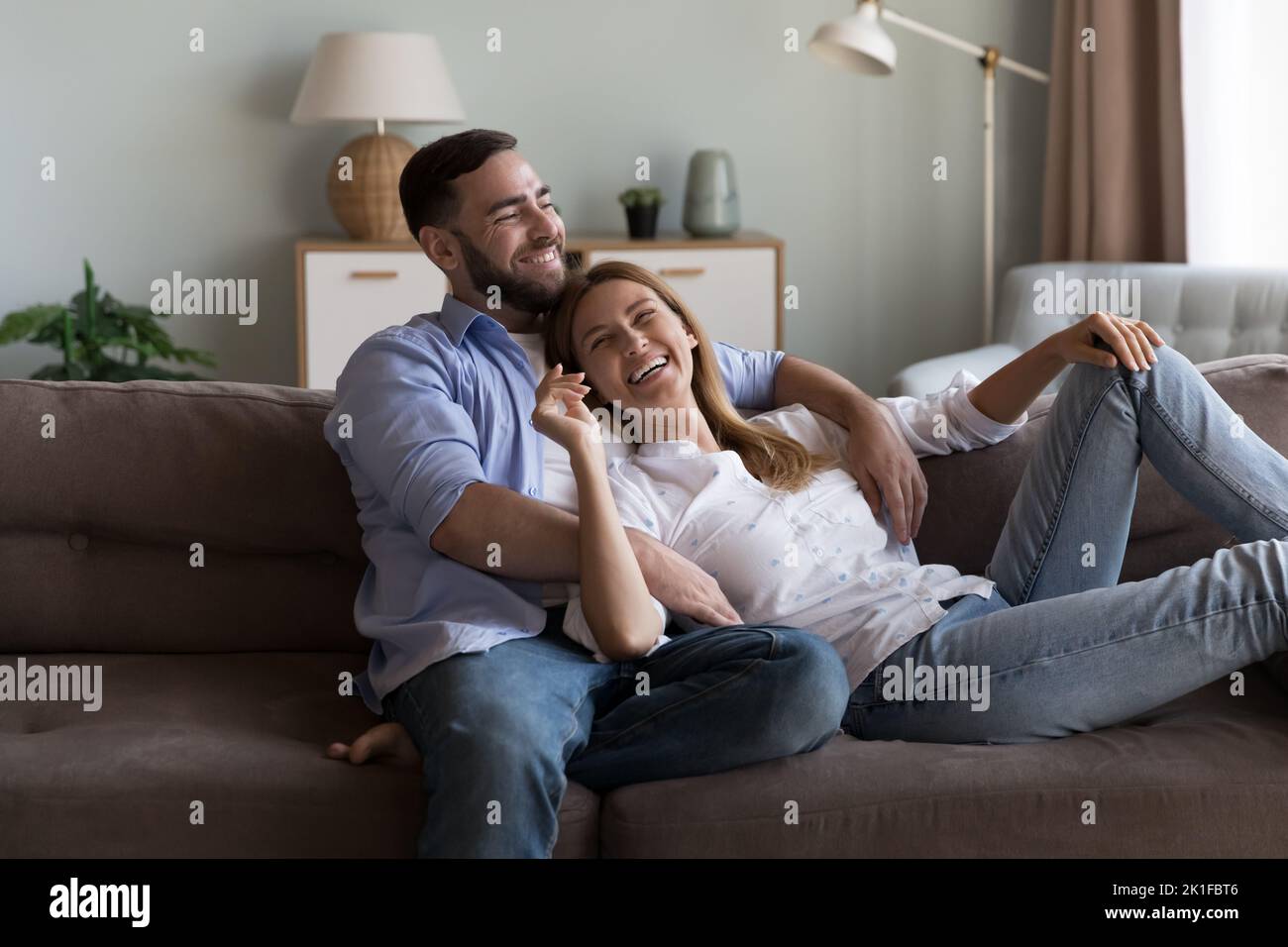 Cheerful dreamy married couple enjoying leisure on sofa Stock Photo
