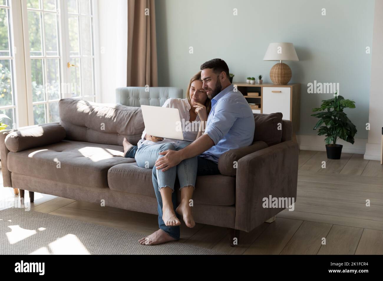 Young millennial couple sharing laptop on couch Stock Photo
