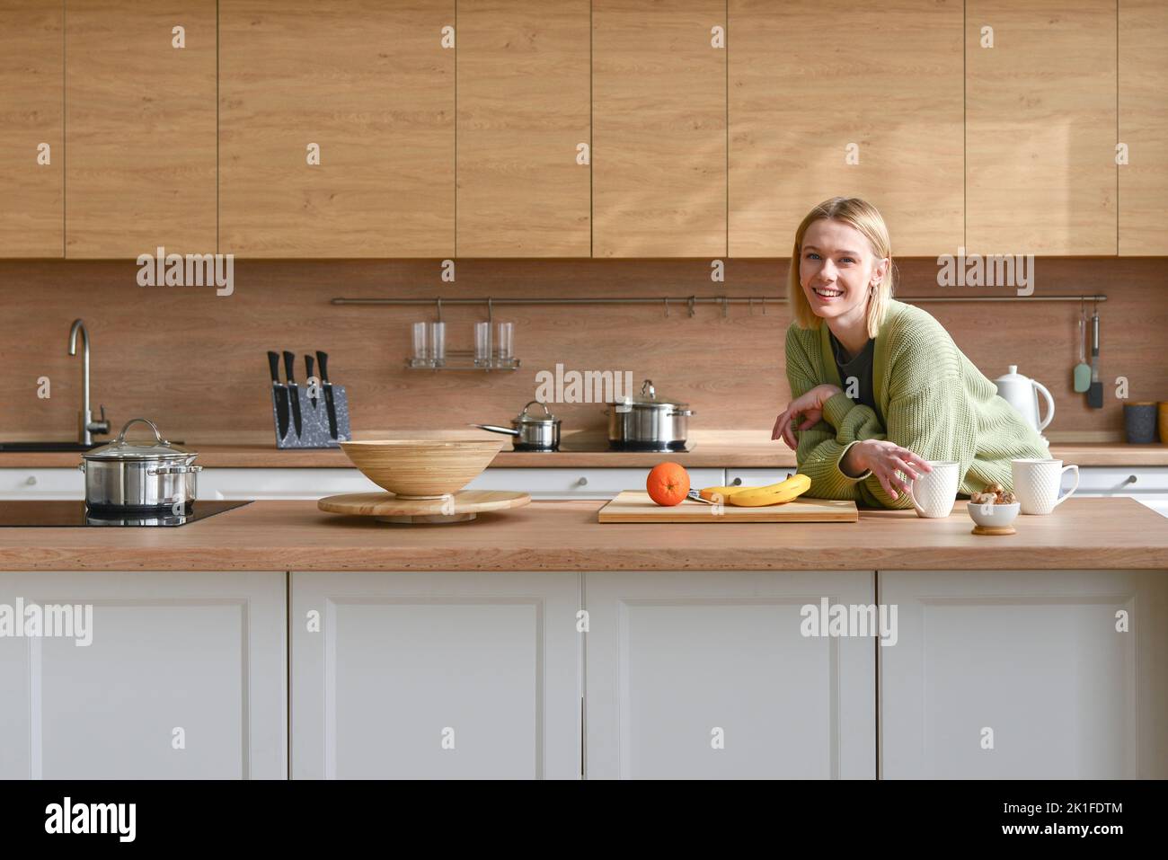 Portrait of a young woman at home in kitchen looking at camera with smile. Stock Photo
