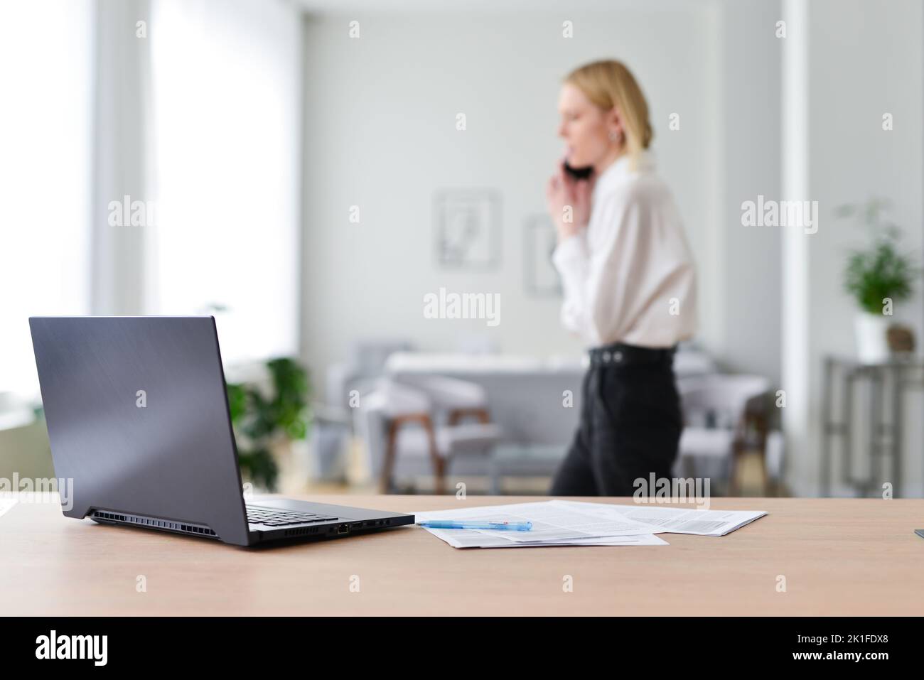 Woman talks on the phone and walks around her workplace. Stock Photo