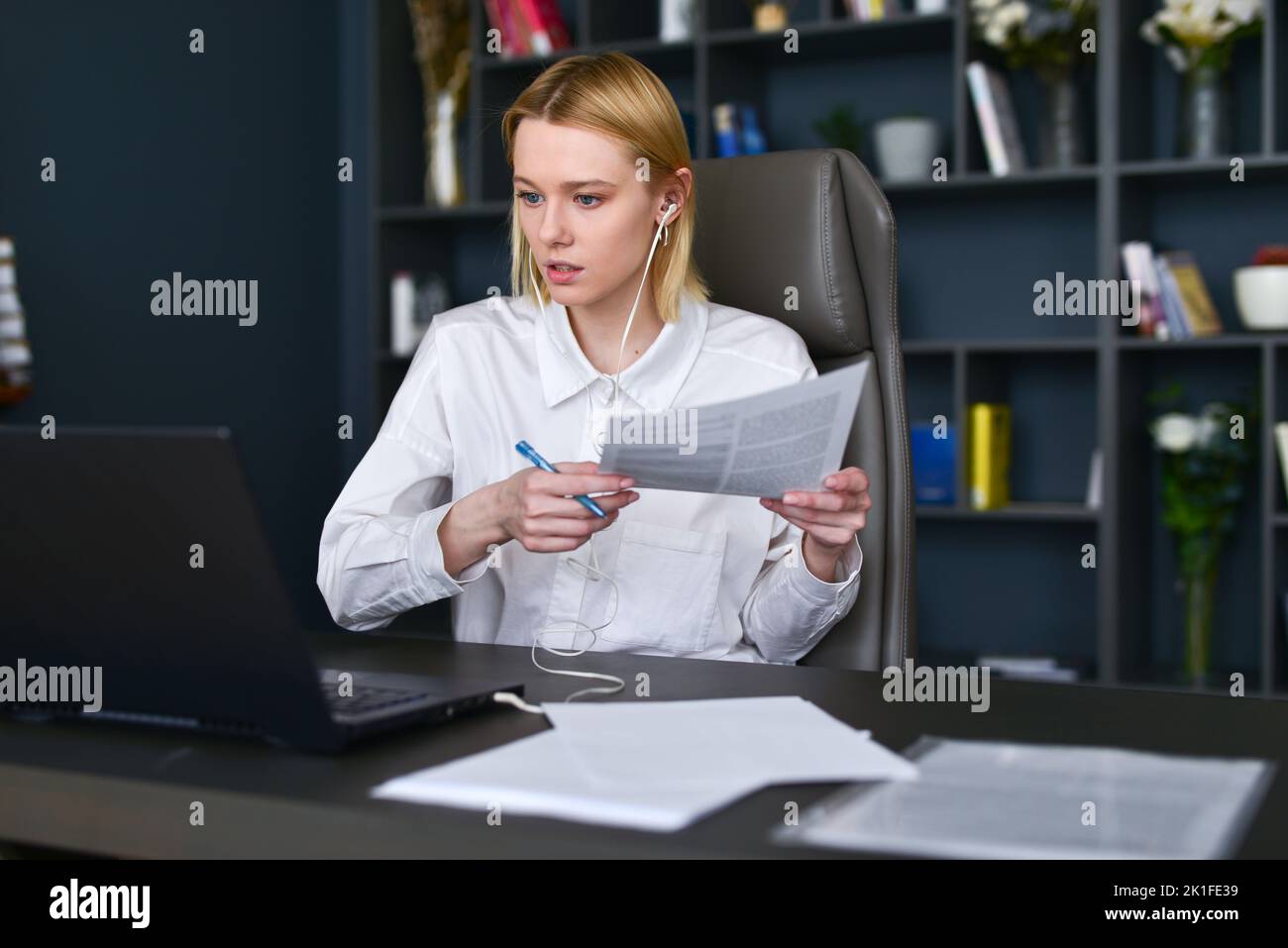 Woman working on laptop and paperwork in office. Stock Photo