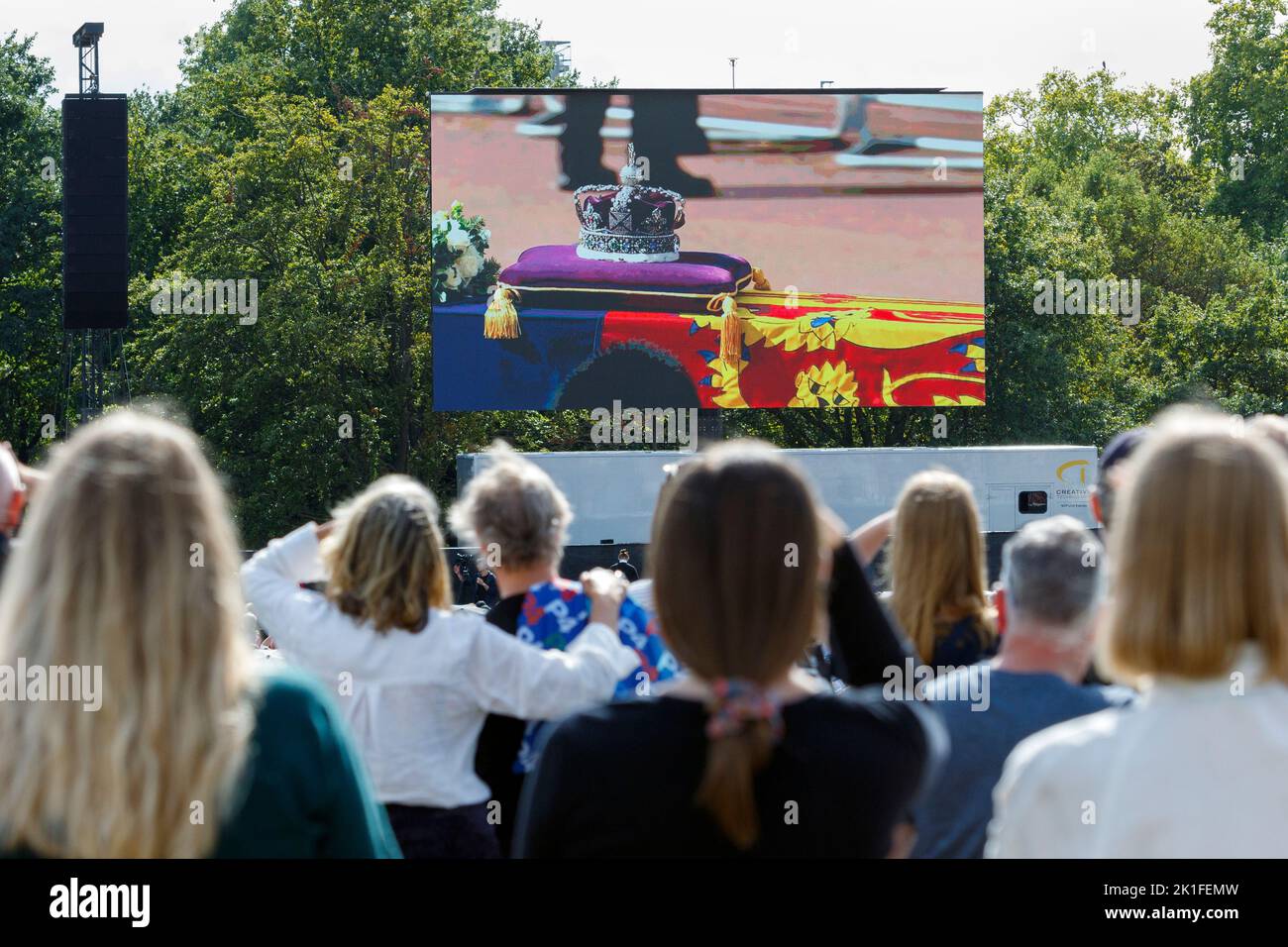 Crowds in Hyde Park are pictured watching Her Majesty the Queen's coffin being transported to the Palace of Westminster on large video screens. Stock Photo