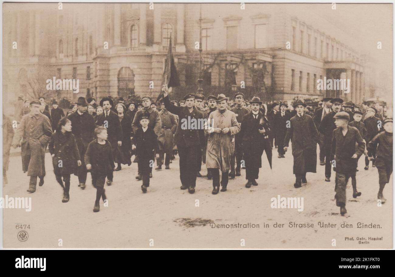 Demonstration in der Straße Unter den Linden / Demonstration in Berlin on the Strasse Unter den Linden during the November 1918 German Revolution. A crowd of men, women and children are walking in the middle of the street. Some of the men are in military uniform, including a sailor who is holding up a red flag. The photograph was sold as a postcard by Postcard by Gebr. Haeckel, Berlin. Stock Photo