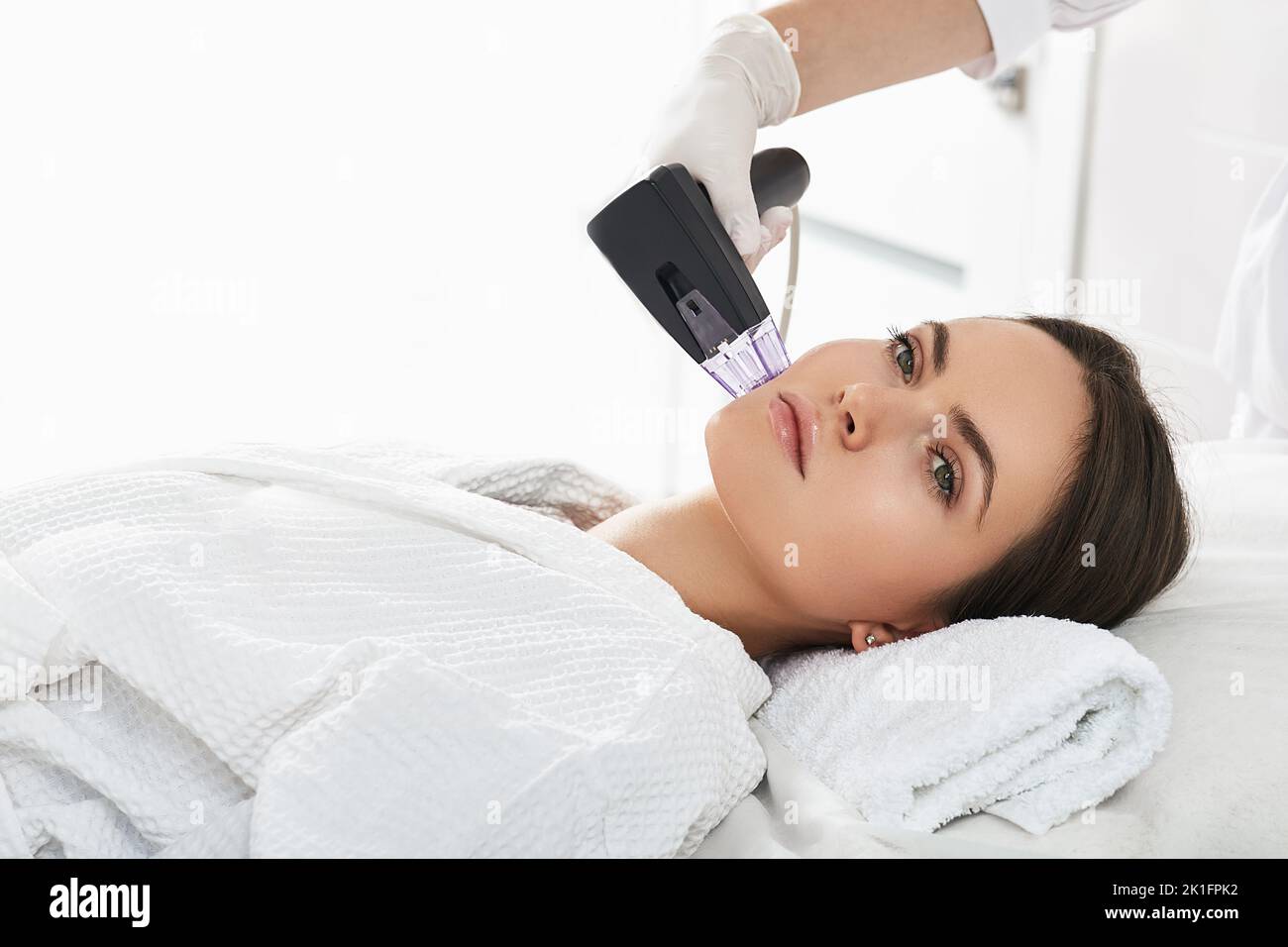 Woman while RF lifting procedure for her face skin tightening with cosmetologist at a beauty salon Stock Photo