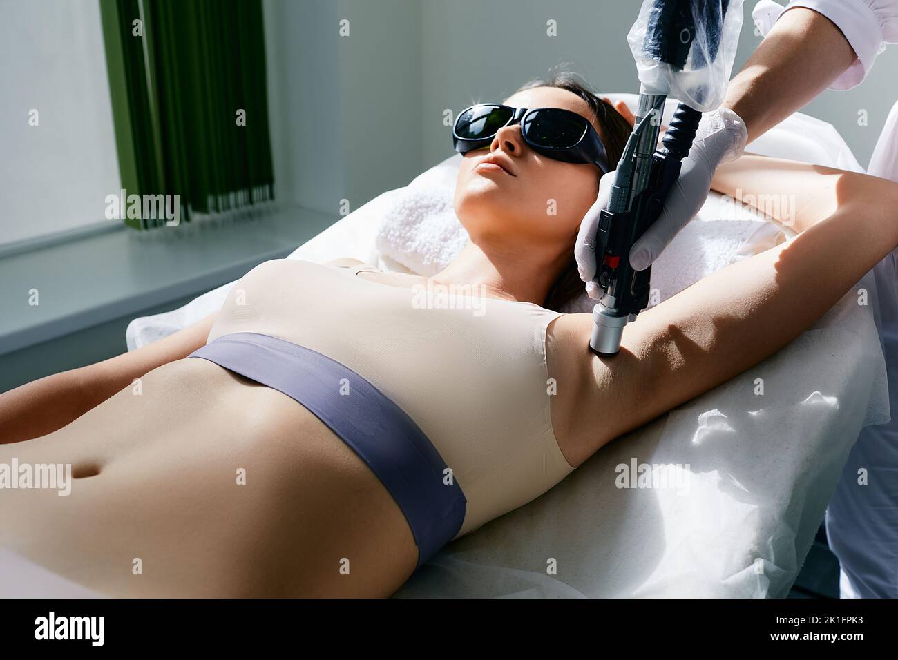 Woman during underarm laser hair removal and armpit laser epilation at beauty center. Armpit laser hair removal procedure Stock Photo