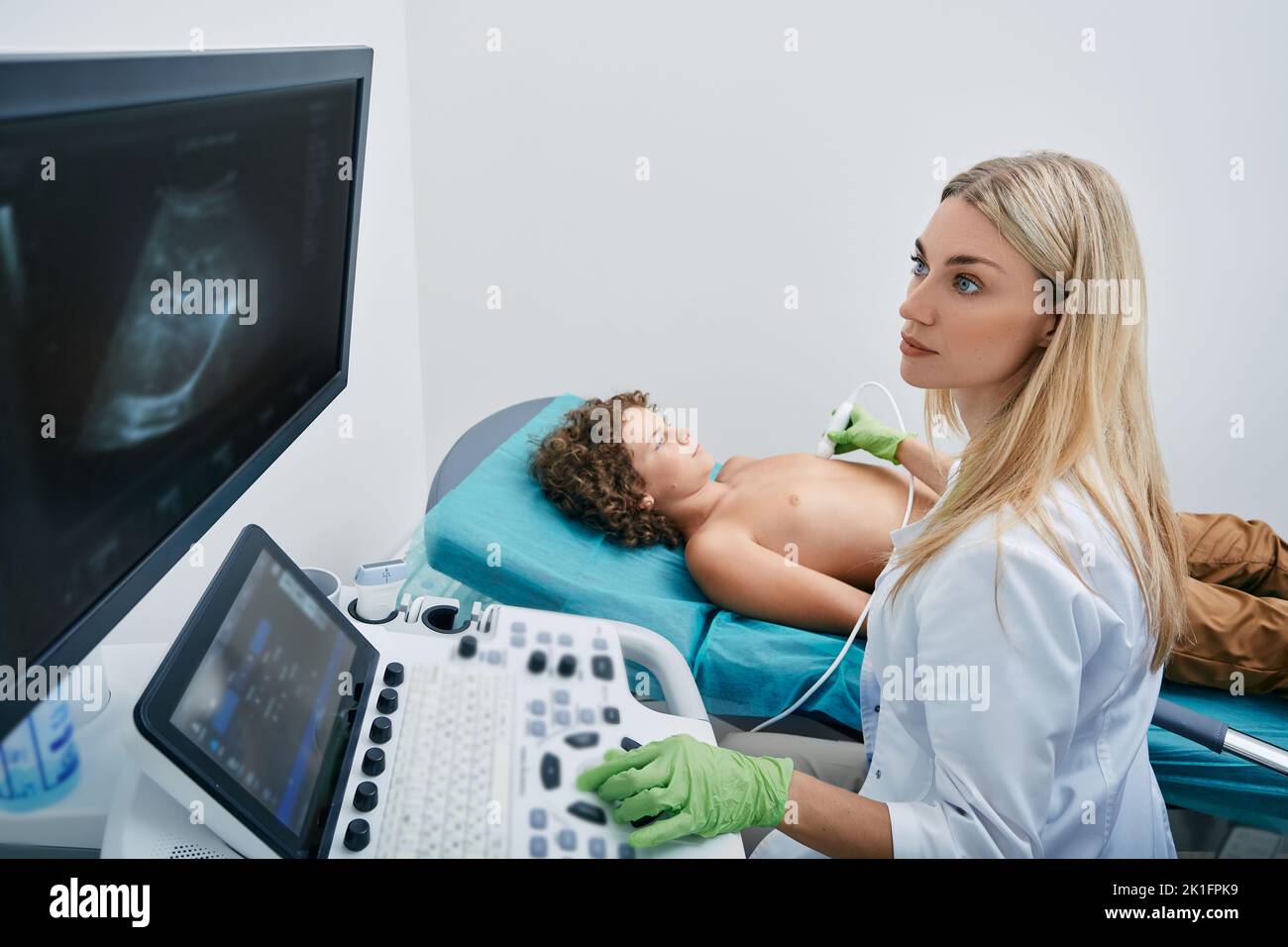 Heart ultrasound exam for male child with ultrasound specialist while medical exam at pediatrics Stock Photo